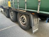 un semi-remorque vert à plateau garé sur le bord de la route