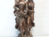statue d'une femme tenant un enfant et un oiseau, posée sur un socle