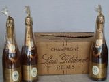 four bottles of champagne in front of a cardboard box on a table