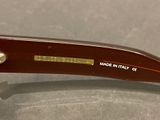 brown sunglasses with a gold bar on the side of the glasses