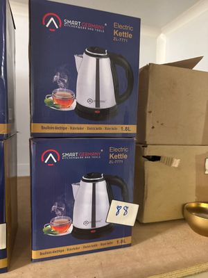 trois cartons contenant des bouilloires électriques posés sur un plan de travail