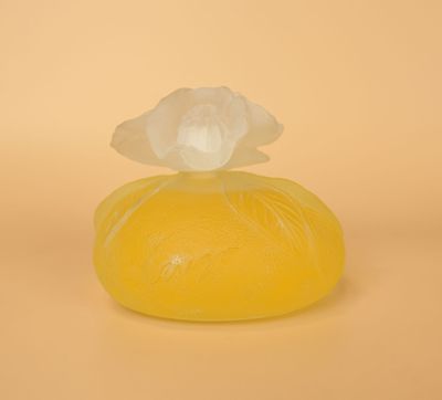 un savon jaune surmonté d'une fleur, posé sur une surface jaune