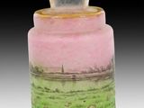 un vase rose et vert posé sur une surface blanche