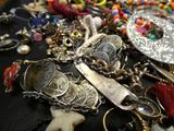 a lot of jewelry on a table with scissors and other items