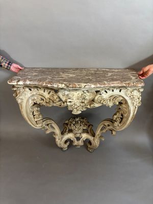 someone is holding a marble top table in front of a gray wall