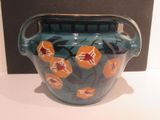 a blue vase with orange flowers on it sitting on a table