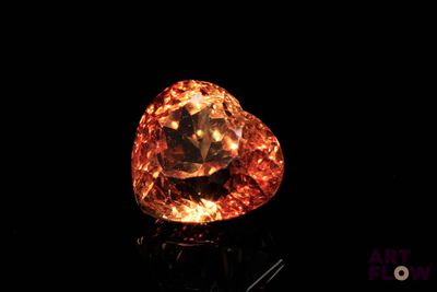 a close up of a large orange diamond on a black surface