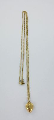 gros plan d'un collier en or sur une surface blanche