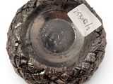 an old silver ashtray with a label on it on a white surface