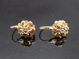 une paire de boucles d'oreilles en or et diamants posées sur un fond noir