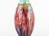 un vase coloré avec une anse dorée sur fond blanc