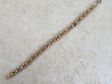 a close up of a gold bracelet on a white surface