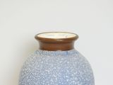 a blue vase sitting on a table with a white wall behind it