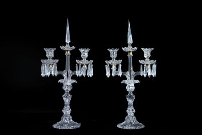 une paire de lustres en cristal avec des bougeoirs sur fond noir