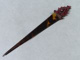 une broche en écaille de tortue ornée d'une perle rouge