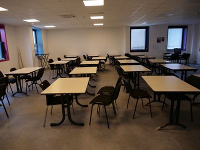 many tables and chairs in a room with a projector screen