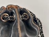 black leather purse with gold zippers and chains on a white surface