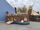 un bateau pirate gonflable avec un toboggan devant un bâtiment bleu