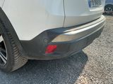 the rear end of a white car parked in a parking lot
