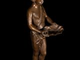 a bronze statue of a boy holding a bird on a black background