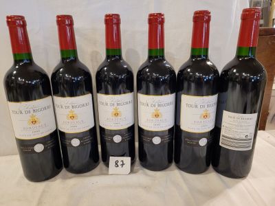 six bottles of red wine are lined up on a table