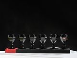 four black and white wine glasses are lined up in a row