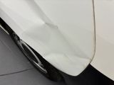 a close up of a white car with a denting on it