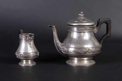 une théière en argent et une tasse en argent posées sur une table
