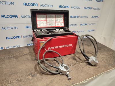 une boîte rouge posée sur une table, avec un tuyau et une paire de ciseaux à l'intérieur