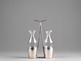 pair of silver vases on a white surface with a gray background