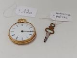 une montre de poche en or et une clé posées sur une table blanche