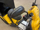a yellow scooter that is parked in a parking lot