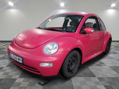 une Coccinelle VW rose garée dans une salle blanche au sol à carreaux