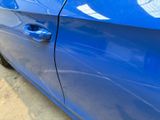 a close up of a blue car door with a hole in the side