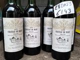 quatre bouteilles de vin rouge sont alignées sur une table