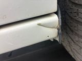 a close up of a car ' s bumper with a rusted tire