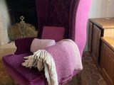 un fauteuil violet recouvert d'une couverture, placé devant une cheminée