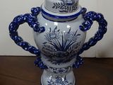 a blue and white vase with a lid on a wooden table