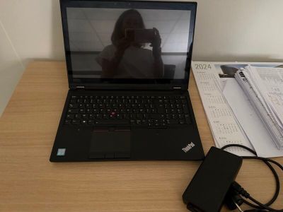 un ordinateur portable posé sur un bureau, à côté d'un chargeur