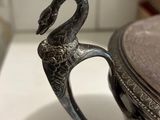 a silver cup with a swan handle on a counter