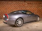 a silver sports car parked in front of a brick wall