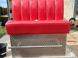 the back end of a red couch in a trailer with a bucket on it