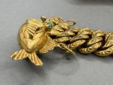 a close up of a gold bracelet with a bird on it