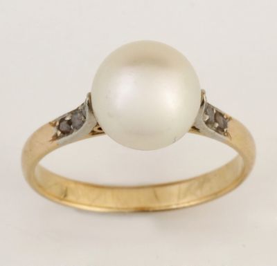 gros plan d'une bague en perles et diamants sur fond blanc