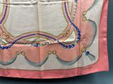 pink silk scarf with blue beads and tassels on a blue background