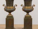 pair of antique bronze vases on pedestals on a table