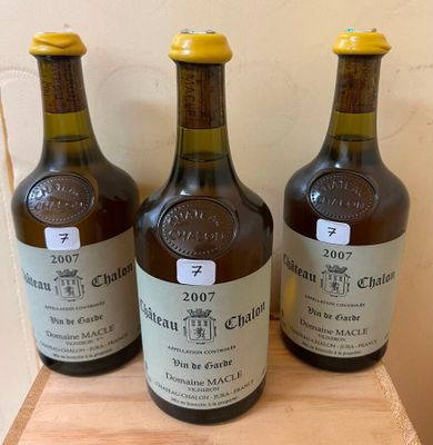 three bottles of wine sit on a wooden shelf in front of a wall