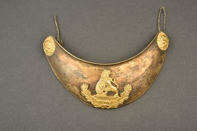 une image représentant un collier plaqué or orné d'un lion et d'un oiseau