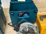une boîte bleue contenant une scie circulaire, à côté d'une boîte à outils jaune