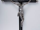 un crucifix en argent sur une croix en bois noir, sur fond blanc